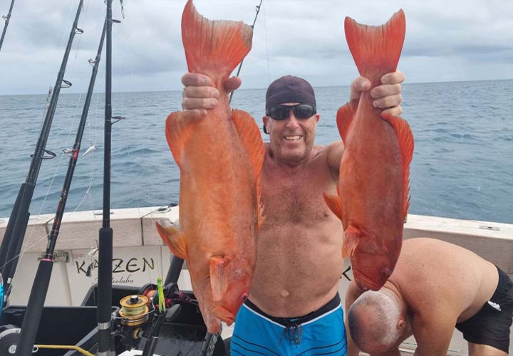 A man holding two large fish on Kaizen Sport Fishing Charters
