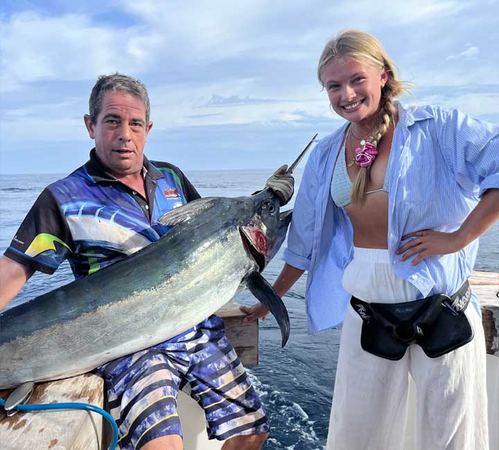 A woman standing next to a man holding a huge Marlin Fish on the Kaizen Sports Fishing Charter Boat